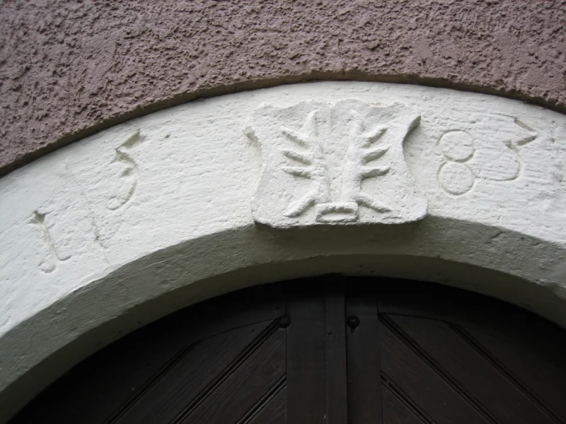 Weiß gestrichener Türbogen, im Scheitel ein Wappenschild mit Hirschstangen, links und rechts die Jahreszahl 1583.