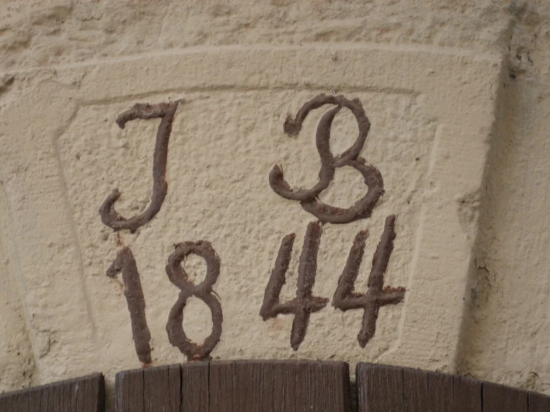 Hell verputzter Schlussstein mit den dunklen Initialen J B und der Jahreszahl 1844.
